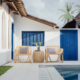 Fotografia de exterior de casa de playa con piscina, pintada de blanco con ventanas y puertas azules